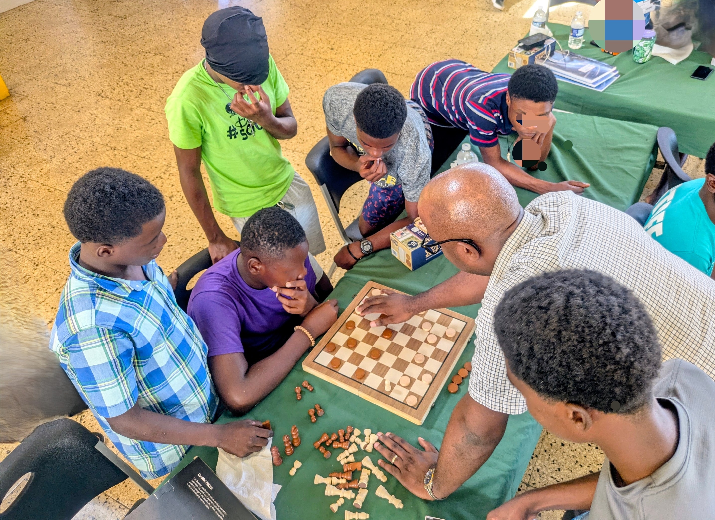 Adults and youth playing checkers together at a community event